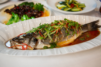 Steamed whole fish with ginger, spring onions, and chili, a traditional Cantonese dish at Mo Jasmine Zurich.