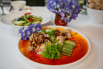 Authentic Sichuan Saliva Chicken (Kou Shui Ji) with spicy chili oil and cucumber, a specialty at Mo Jasmine Zurich.