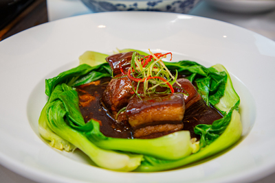 Dongpo Pork, tender slow-braised pork belly served with bok choy, a classic Chinese dish at Mo Jasmine Zurich.