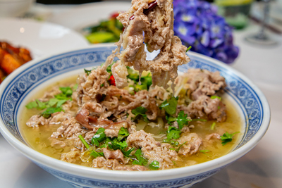 Tender sliced beef or pork in a flavorful Sour Cabbage Soup (Suan Cai) with herbs, served at Mo Jasmine Zurich.