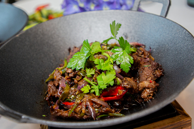 Sizzling Stir-fried Beef with onions, peppers, and cilantro in a hot wok at Mo Jasmine Chinese restaurant in Zurich.