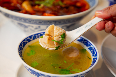 Clear Chinese soup with tender fish balls or meatballs, garnished with cilantro, a comforting dish at Mo Jasmine Zurich.