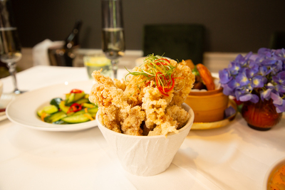 Crispy fried chicken or fish bites, garnished with chili and spring onion, a popular appetizer at Mo Jasmine Zurich.